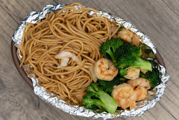 Overhead view of delicious basket of grilled shimp and chow mein noodles with vegetables for a tasty seafood meal