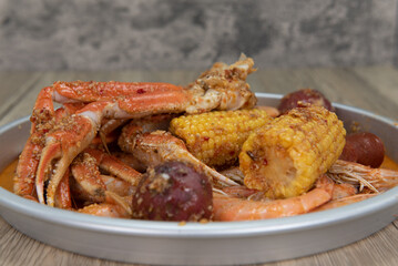 Delicious buttery plate of boiled snow crab legs with corn on the cob and sausage for a tasty seafood meal