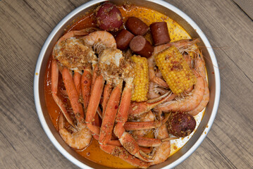 Overhead view of delicious buttery plate of boiled snow crab legs with corn on the cob and sausage...