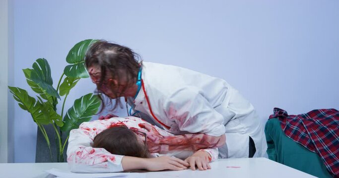 Mustachioed male zombie with bloody face and in medical uniform killed young woman, and now bites off pieces of meat from her lying on table. Halloween party in style of zombie apocalypse