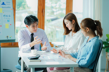 Asian and Caucasian corporate executives discuss business in a conference room of three young businessmen and women discussing tech startups about product roadmaps, and collaboration ideas.