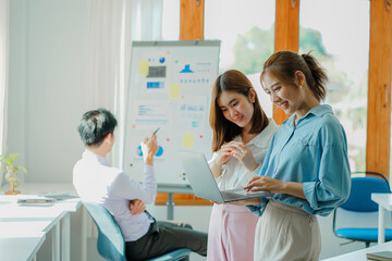 Asian and Caucasian corporate executives discuss business in a conference room of three young businessmen and women discussing tech startups about product roadmaps, and collaboration ideas.