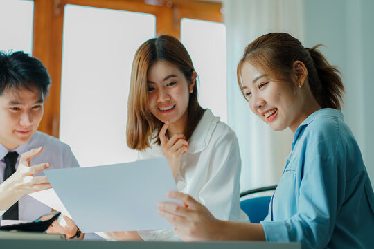 Asian and Caucasian corporate executives discuss business in a conference room of three young businessmen and women discussing tech startups about product roadmaps, and collaboration ideas.