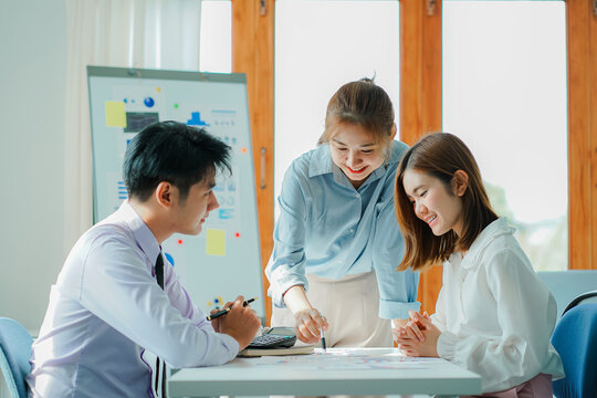 Asian and Caucasian corporate executives discuss business in a conference room of three young businessmen and women discussing tech startups about product roadmaps, and collaboration ideas.