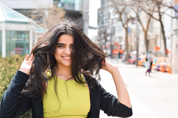 Portrait of happy young girl smiling looking at camera on city street