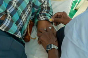 Kolkata, West Bengal, India - 25th February 2018 : Indian male volunteer donating blood at blood donation camp, with blood transfusion medical instruments.
