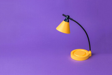 A yellow table lamp on a dark purple background.