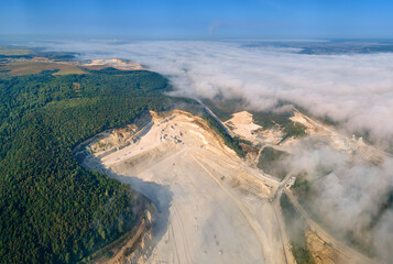 Aerial view of open pit mining of limestone materials for construction industry with excavators and dump trucks