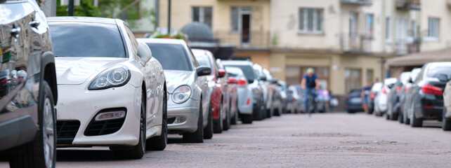 Cars parked in line on city street side. Urban traffic concept