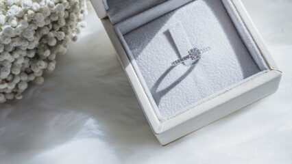 Close up of diamond ring with white flower, sunlight and shadow background. Love, valentine, relationship and wedding concept. Soft and selective focus.