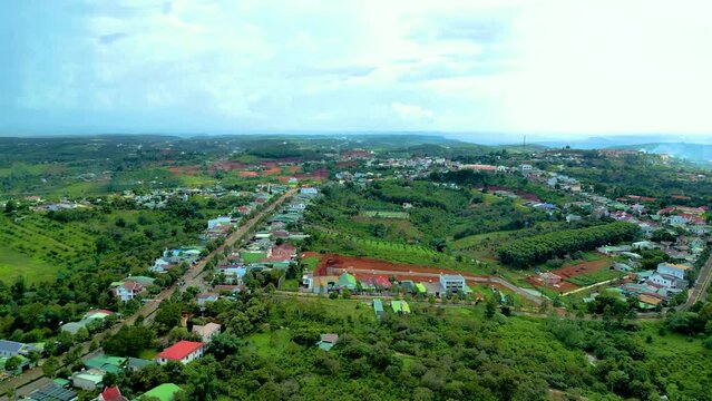 Aerial panorama view of National Route 14 in Kien Duc town, Dac Nong province, Vietnam with hilly landscape, sparse population around the roads and Dak R'tang lake.