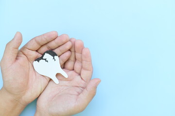 Tooth decay and dental cavities care concept. Top view of hands holding a big white tooth with...