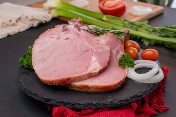 Two pieces of raw pork chop with onion and cherry tomatoes