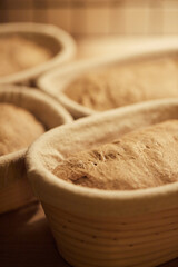Process of making wheat bread at home. Proofing of the dough in rattan baskets. The concept of healthy homemade food. Vertical photo.