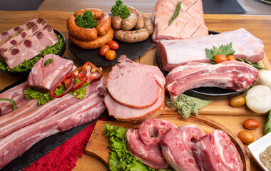 Assorted beautiful raw pork pieces including chop, sausage, rib, steak
