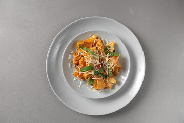 Pasta pappardelle with beef ragout sauce in grey bowl. Grey background