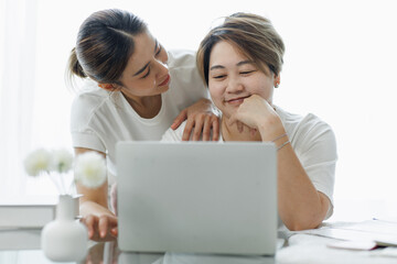 Fototapeta premium Happy lgbt gay couple of Asian women having fun using a computer laptop at home - LGBT lesbian relationship, Asian LGBTQ female lesbian concept.