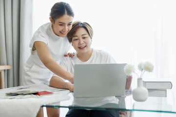 Happy lgbt gay couple of Asian women having fun using a computer laptop at home - LGBT lesbian relationship, Asian LGBTQ female lesbian concept.