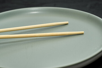 grey plate and chopsticks on a black background