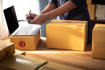 Young entrepreneur business owner work at home, small business startup receive order client and take note working with report and pack the product on purchase delivery online to sending destination.