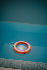 in the blue water of a swimming pool floats one red life ring