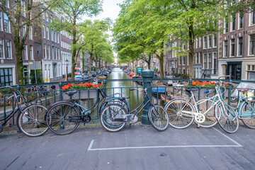 Fototapeta na wymiar Amsterdam. Parked bikes on a bridge over canal and moored boat and houseboat on water. Netherlands