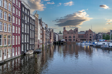 Amsterdam house, reflection in canal water at dusk. Touristic district Damrak, Netherlands Holland