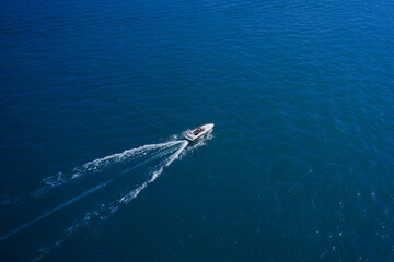 Top view of the boat. Top view of a white boat sailing in the blue sea. A boat with a motor on blue water. Aerial view luxury motor boat.