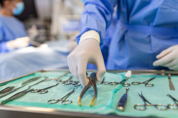 Obraz premium Operating Room of Surgical Table with Instruments, Assistant Picks up Instruments for Surgeons During Operation. Surgery in Progress. Professional Medical Doctors Performing Surgery.