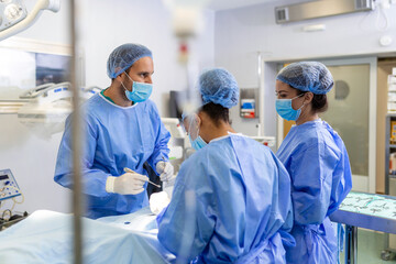 A surgeon's team in uniform performs an operation on a patient at a cardiac surgery clinic. Modern...
