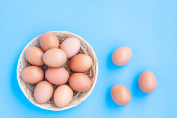 Chicken Eggs in a basket on blue with grain background