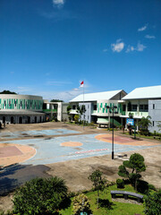 School building in Indonesia on a sunny day features a spacious courtyard with a basketball court...