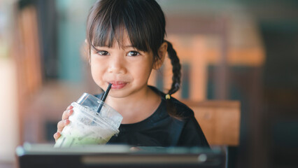 Cute asian children drinking fresh juice in the cafe