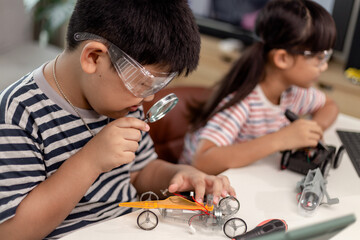 two Asian children having fun learning coding together, learning remotely at home, STEM science,...