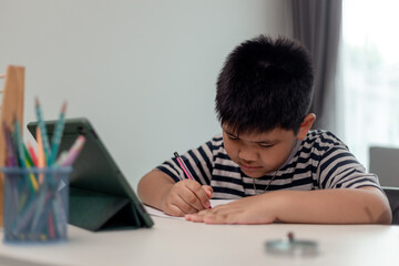 Cute Asian child learning class study online with video call from tablet at home .Social distancing concept