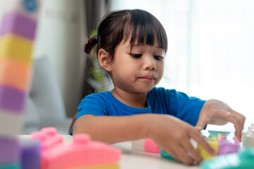 Adorable little girl playing toy blocks in a bright room