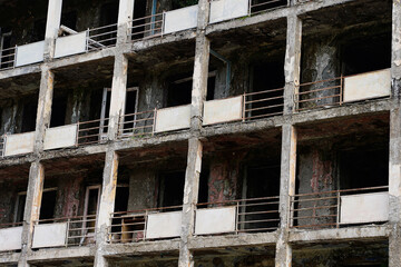 Close up fragment of an abandoned residential multi-storey building. Destroyed balconies, lack of windows and doors