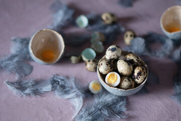 quail eggs in ceramic vases, gray feathers on the table, easter still life,