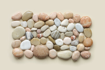 Fototapeta na wymiar Aesthetic minimal pattern with set of sea pebble stones on beige background. Square composition from natural round smooth stone neutral color. Collection of rocks, summer concept, top view