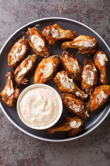American Alabama White Sauce Chicken Wings closeup in the plate on the table. Vertical top view from above