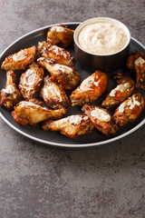 Grilled chicken wings with Alabama white sauce close-up in a plate on the table. Vertical