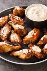 American Alabama White Sauce Chicken Wings closeup in the plate on the table. Vertical
