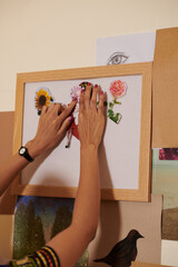 Hands of female artist working on collage and glueing cut pictures and photos on paper