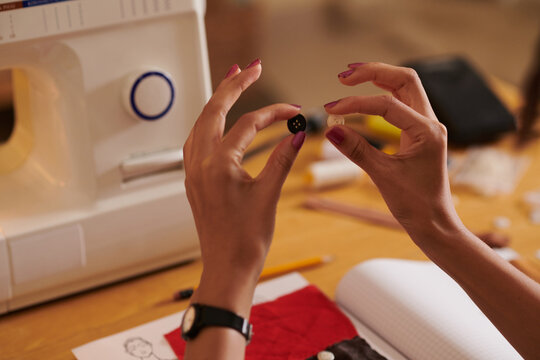 Close-up image of woman choosing between black and white buttons she is making