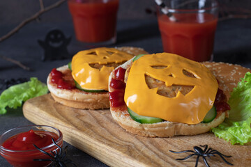 Two funny monster chicken burgers with toast cheese, ketchup and cucumber. Creative Halloween food
