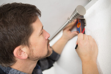 Fototapeta premium man using spirit level to check curtain rail