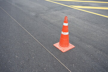 Red rubber cones are placed in the paved road.