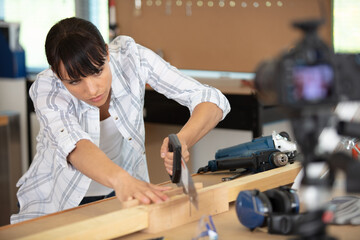 female carpenter using electric sander for wood