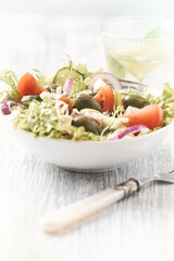 Salad with Green Olives, Tomatoes and Feta Cheese. Bright wooden background. Close up.