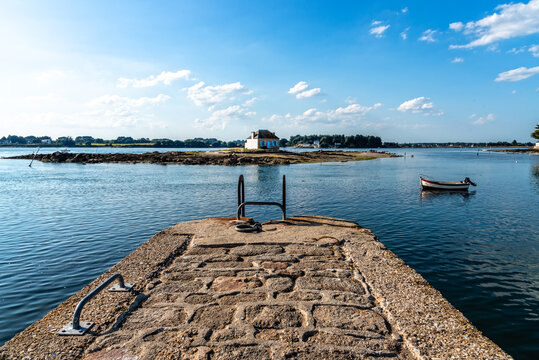 Small island with a cottage in the Etel River, Ile de Saint-Cado, Brittany, France. House in water with fishing boats